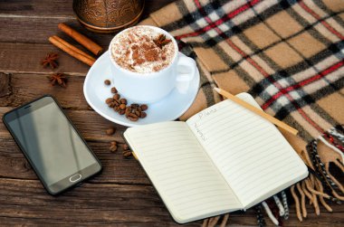 Rahat tatil. Kahve kupa, defter, kalem, telefon, ekose ve kahve fasulye. Yukarıdan görüntülemek