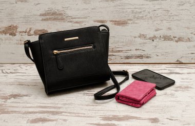 Küçük siyah kadın çanta, çanta ve telefon ahşap arka plan üzerinde. Moda kavramı