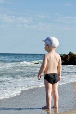 Küçük sarışın çocuk sahilde dalgalar seyir