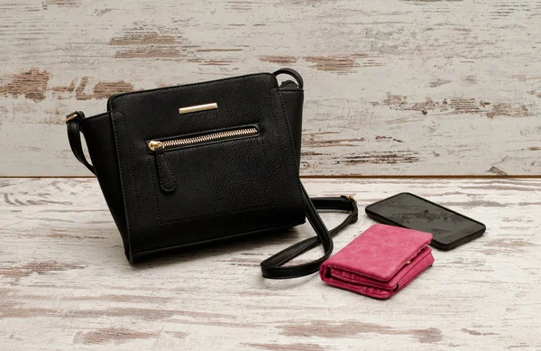 Küçük siyah kadın çanta, çanta ve telefon ahşap arka plan üzerinde. Moda kavramı — Stok fotoğraf