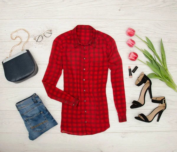 Modekonzept. rote Bluse, Jeans, Handtasche, Sonnenbrille, schwarze Schuhe, Lippenstift und rosa Tulpen. Ansicht von oben, heller Holz-Hintergrund — Stockfoto