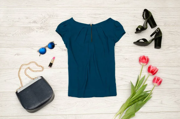 Concepto de moda. Blusa azul, bolso, gafas redondas, lápiz labial, zapatos negros y tulipanes rosados. Vista superior, fondo de madera clara — Foto de Stock