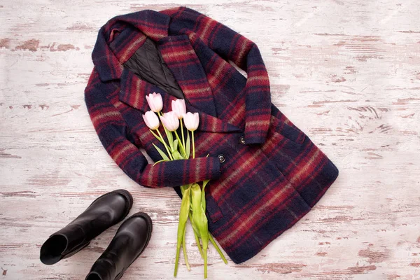 Manteaux à carreaux chauds, chaussures noires, tulipes. Concept à la mode, vue de dessus, fond en bois — Photo