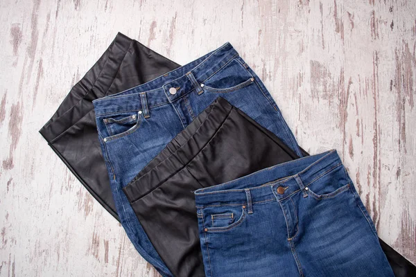 Niebieskie dżinsy i czarne skórzane legginsy, asortyment. Koncepcja modne. Od góry — Zdjęcie stockowe