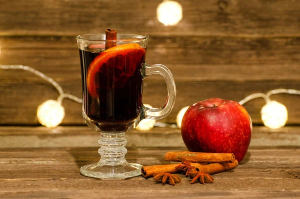 Εσωτερικη κούπα ζεστό κρασί με μπαχαρικά. Apple, ραβδιά κανέλας και το γλυκάνισο σε ένα ξύλινο τραπέζι, φανάρια στο παρασκήνιο — Φωτογραφία Αρχείου