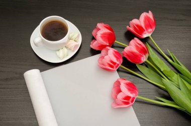 Kahve kupa, hatmi, temiz bir sayfayla ve Pembe Lale. Siyah tablo. Üstten Görünüm