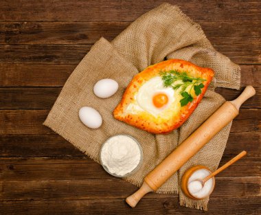 Gürcü mutfağı. Khachapuri yas, tuz, un, yumurta ve maydanoz üzerinde ahşap bir masa üzerinde yumurta ile