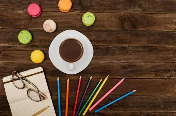Kahve kupa, bademli kurabiye, renkli kalemler ve ahşap bir zemin üzerine gözlük ile not etmek. Üstten Görünüm, boşaltmak