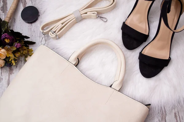 Moda kavramı. Hafif çanta, siyah ayakkabı ve beyaz bir arka plan üzerinde çiçekler. Üstten Görünüm