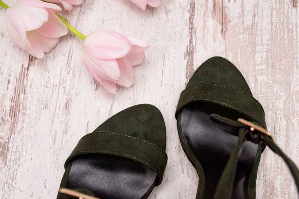 Parte de sapatos de camurça verde em um fundo de madeira, tulipas rosa. Conceito elegante. Vista superior . — Fotografia de Stock