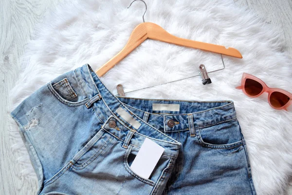 İki kot şort ile boş bir iş cep, beyaz kürk ve pembe gözlüklerini içinde kart. Üstten Görünüm