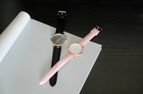 Deux montres-bracelets sont noires et roses, sur une feuille grise. Espace pour le texte. Concept à la mode, vue de dessus — Photo