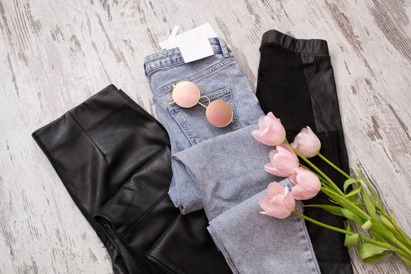 Spijkerbroek en zwart lederen broek, bril, roze tulpen. Modieuze concept. Bovenaanzicht — Stockfoto