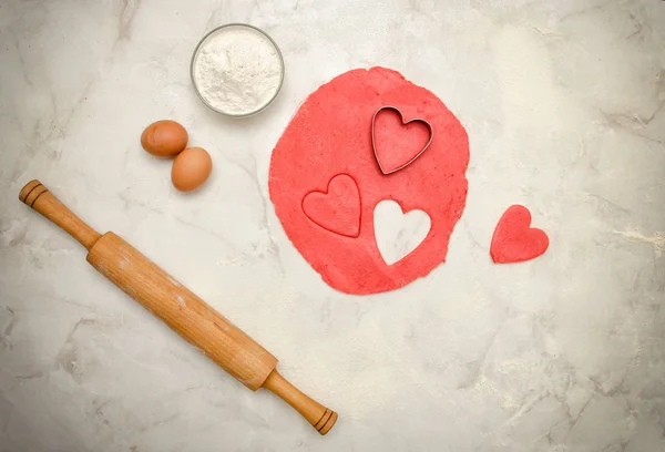 Kırmızı hamur Kalpler, yumurta, un ve beyaz bir tablo üzerinde oklava dışarı bir kesim ile. Üstten Görünüm — Stok fotoğraf