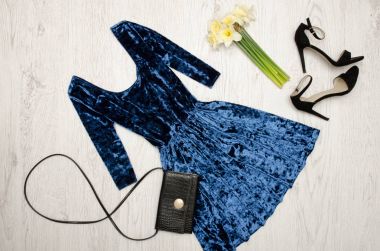 Mavi kadife elbise, siyah ayakkabılar, debriyaj ve Nergis bir buket. Moda kavramı. Ahşap arka plan. Üstten Görünüm