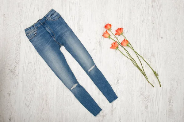 蓝色牛仔裤及橙色玫瑰木的背景上。时尚概念，顶视图 — 图库照片