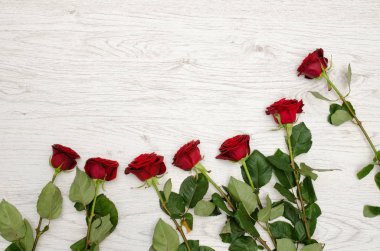 Çerçevenin üstten görünüm kenarında hafif ahşap arka plan üzerinde koyu kırmızı gül. Metin için yer