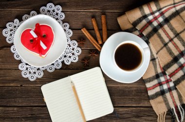 Rahat tatil. Kupa kahve, heartshaped gingerbread, not defteri ve kalem, ekose ve baharat. Üstten Görünüm