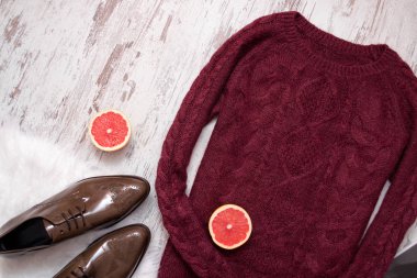 Kestane rengi örme kazak, kahverengi deri ayakkabılar, greyfurt yarım kesilmiş. Ahşap arka plan. Moda kavramı. Üstten Görünüm