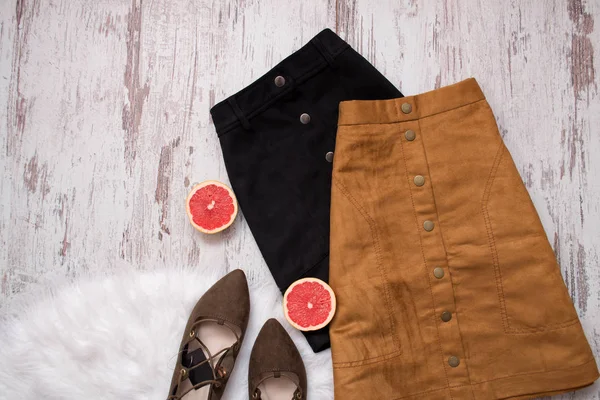 Коричневая и черная замшевая юбка, коричневые замшевые туфли, нарезанные половинки грейпфрута. Деревянный фон. Концепция моды. вид сверху — стоковое фото