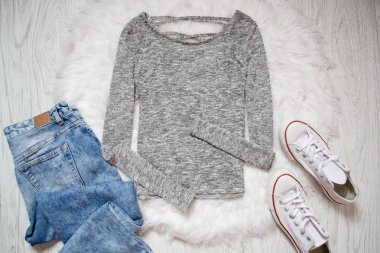 Gri sweatshirt, beyaz spor ayakkabı, kot pantolon. Ahşap arka plan. Moda kavramı, üstten görünüm