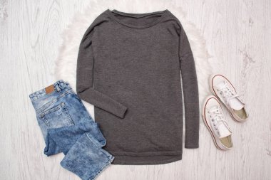 Gri sweatshirt, spor ayakkabı, kot pantolon. Ahşap arka plan. Moda kavramı, üstten görünüm
