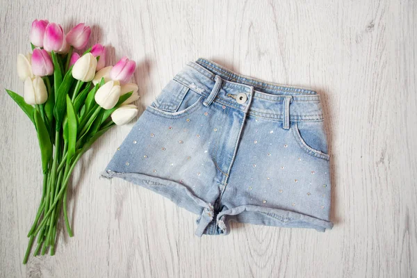 Kurze Jeans-Shorts mit Strass, rosa Tulpen. Modisches Konzept, Draufsicht — Stockfoto