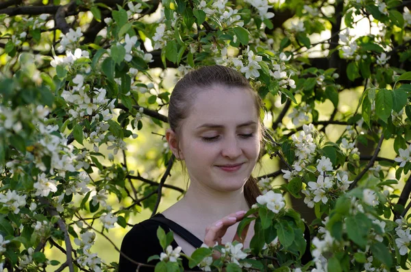 Mujer joven entre las ramas florecientes de un manzano, primavera — Foto de Stock