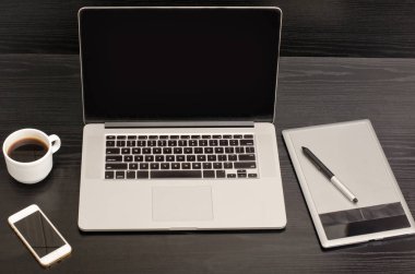 Açık defter, grafik tablet, kahve fincanı ve telefon siyah bir tablo