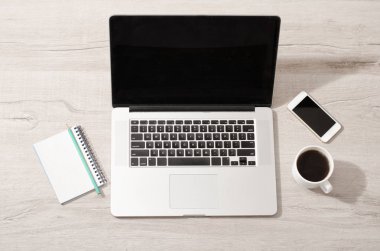 Bir fincan kahve ve bir dizüstü bilgisayar, dizüstü bilgisayar açık, smartphone. Hafif ahşap arka plan, üstten görünüm