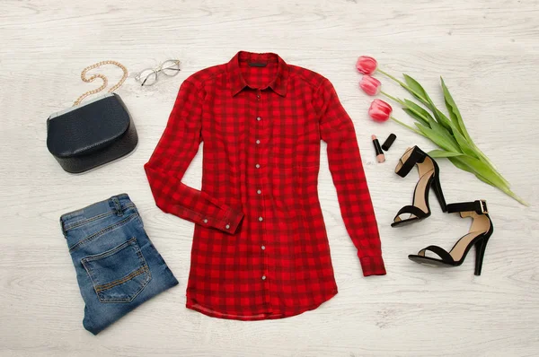 Concepto de moda. Blusa roja, jeans, bolso, gafas de sol, zapatos negros, lápiz labial y tulipanes rosados. Vista superior, fondo de madera clara —  Fotos de Stock