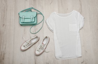 Beyaz bluz, beyaz spor ayakkabı ve nane çanta. Moda kavramı. Ahşap arka plan