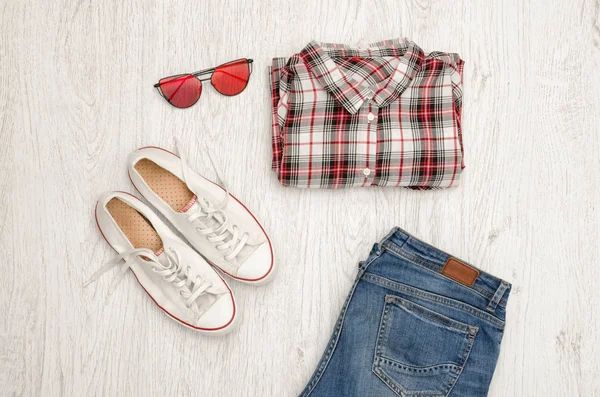 Κόκκινο και άσπρο καρό πουκάμισο, γυαλιά, πάνινα παπούτσια και τζιν. Ξύλινο υπόβαθρο. Μοντέρνα ιδέα, το top view — Φωτογραφία Αρχείου
