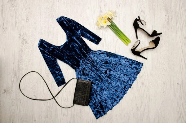 Mavi kadife elbise, siyah ayakkabılar, debriyaj ve Nergis bir buket. Moda kavramı. Ahşap arka plan. Üstten Görünüm