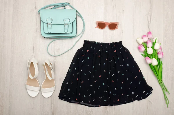 Μαύρη φούστα, γυαλιά, λευκά παπούτσια, τσάντα και ένα μπουκέτο με τουλίπες. Έννοια της μόδας. Ξύλινο υπόβαθρο. — Φωτογραφία Αρχείου
