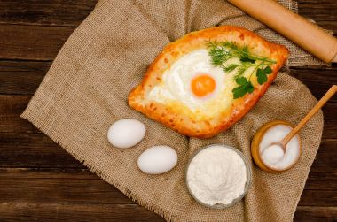 Khachapuri yas, tuz, un ve yumurta üzerinde ahşap masa üzerinde yumurta ile