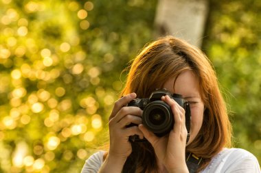 Kız fotoğrafçı yeşil arka planı fotoğraf çeker. Önden Görünüm