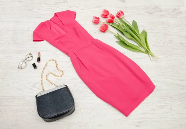 Έννοια της μόδας. Κατακόκκινο φόρεμα, κραγιόν και ροζ τουλίπες. Το Top view, ελαφρύ ξύλο παρασκήνιο — Φωτογραφία Αρχείου