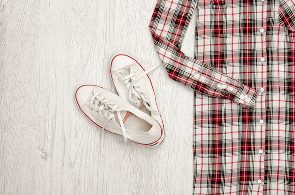 Camisa a cuadros roja y blanca y zapatillas deportivas. Fondo de madera. Concepto de moda, vista superior — Foto de Stock