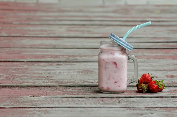 Mug with yogurt and strawberries on red background vintage wooden planks — Stock Photo, Image