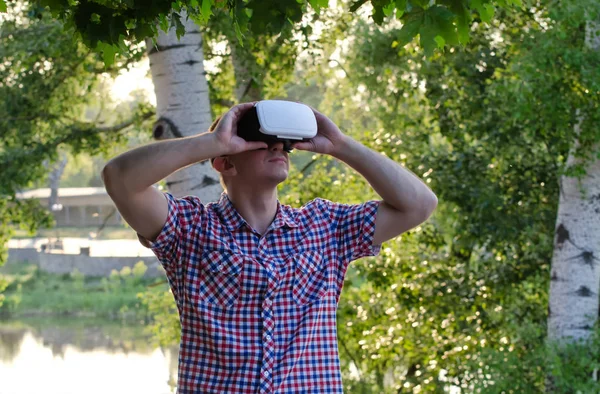 Человек в шлеме виртуальной реальности на фоне природы — стоковое фото
