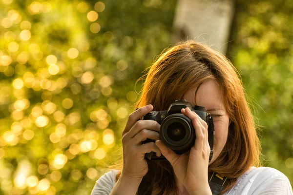 Fotógrafo menina tira fotos contra o fundo da vegetação. Vista frontal — Fotografia de Stock