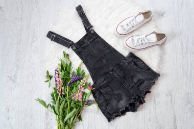 Gri denim tulum, bir buket çiçek, spor ayakkabı. Moda kavramı