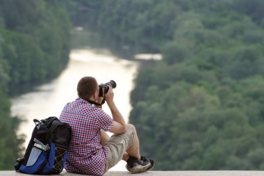 Adam bir Hill orman ve nehir arka planda fotoğraf çeker