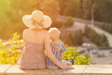 Anne ve oğlu yeşil orman ve köy uzakta arka plan üzerinde oturan