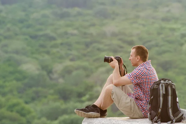 Homem tira fotos de uma colina no fundo da floresta — Fotografia de Stock