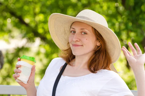 Hermosa chica con sombrero sostiene un vaso de café y posando sobre un fondo verde — Foto de Stock