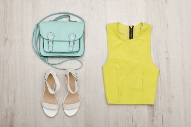 Işık Yeşil bluz, beyaz ayakkabı ve çanta. Moda kavramı. Ahşap arka plan.