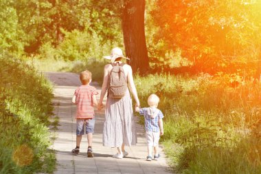 Anne ve oğlu yolun parkta yürüyorduk. Arkadan Görünüm. Güneşli gün