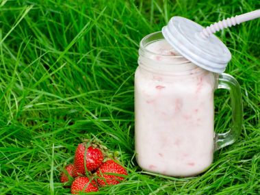 Yoğurt ve çilek yeşil çimen, metin için yer bir arka plan üzerine bir fincan